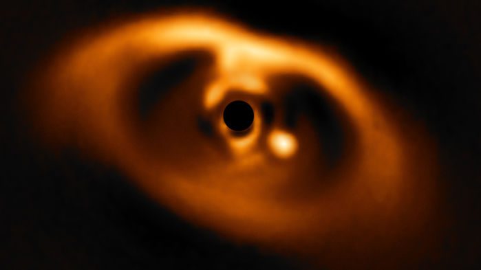 این تصویر تماشایی از تجهیزات SPHERE متعلق به تلسکوپ بزرگ ESO، اولین تصویر واضح از یک سیاره است که در لحظه‌ی تولد در مدار ستاره کوتوله‌ی PDS ۷۰ می‌باشد. این سیاره به صورت یک نقطه‌ی درخشان در سمت راست مرکز تصویر دیده می‌شود. دایره‌ی سیاه مرکزی، ماسک کورونوگرافی است که برای مسدود کردن نور کورکننده‌ی ستاره‌ی مرکزی استفاده می‌شود. (ESO/A. MÜLLER ET AL.)